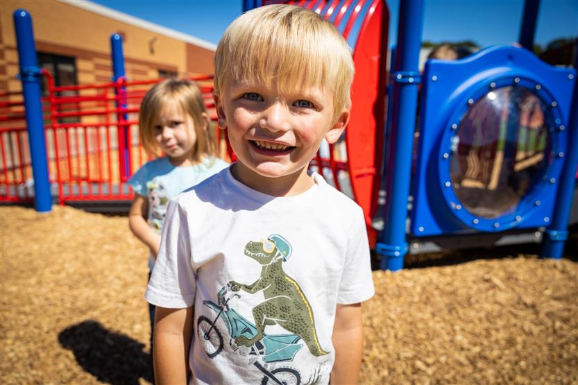 A boy wearing a white shirt smiles